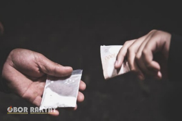 Pematangsiantar, Obor Rakyat – Isu peredaran narkoba di kawasan Bangsal, Siantar Utara, kembali mencuat. Publik digemparkan dengan dugaan bahwa sindikat narkoba yang dikendalikan oleh sosok berinisial UH terus beroperasi tanpa hambatan, bahkan terkesan mendapat perlindungan dari oknum aparat dan media. Nama LL disebut-sebut sebagai koordinator lapangan, sementara puluhan "kenjiro" (istilah lokal untuk informan) diduga menjadi mata-mata yang menjaga kelancaran distribusi barang haram tersebut.